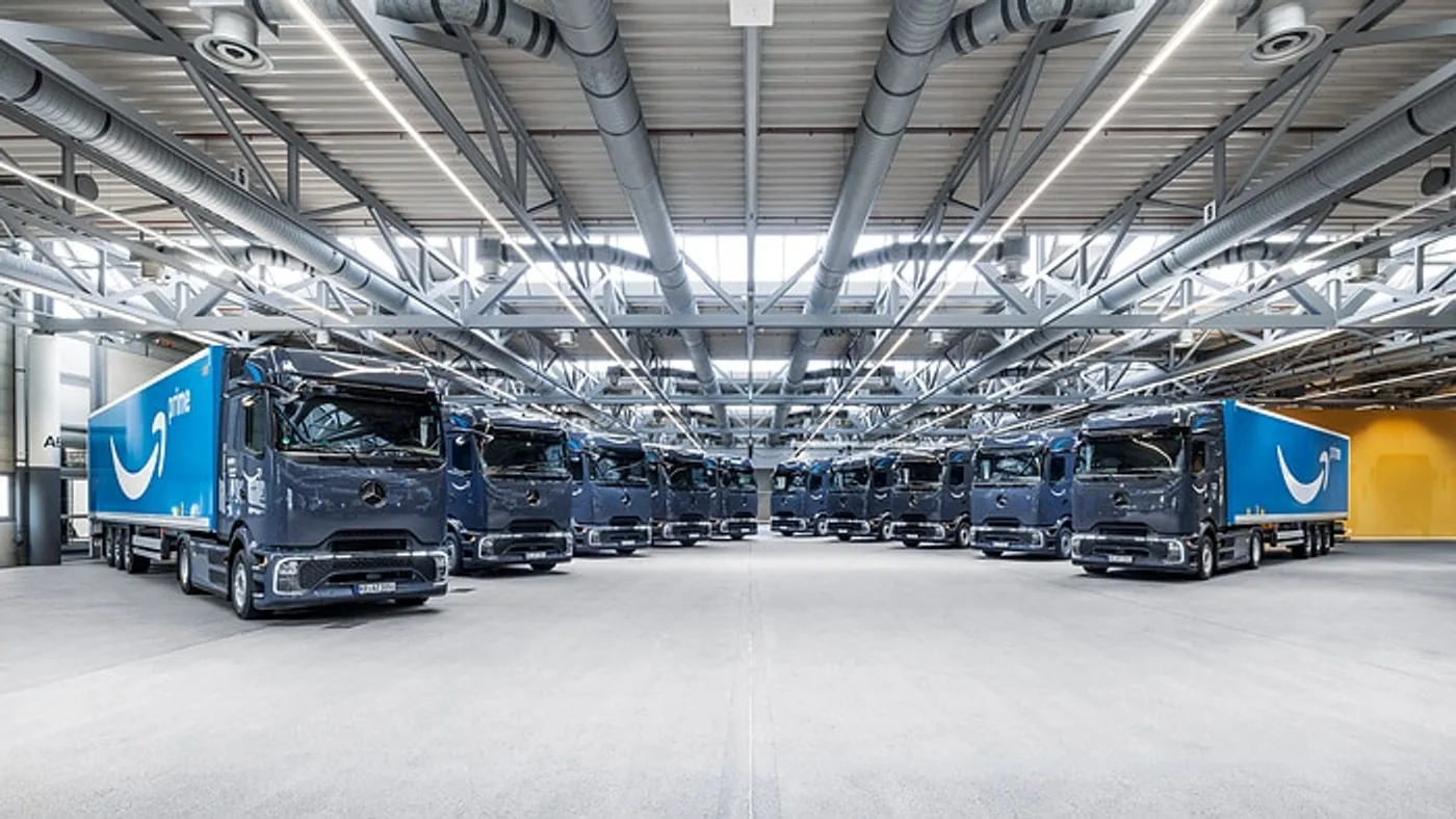 Camiones Mercedes-Benz eActros con semirremolques Amazon alineados en una nave