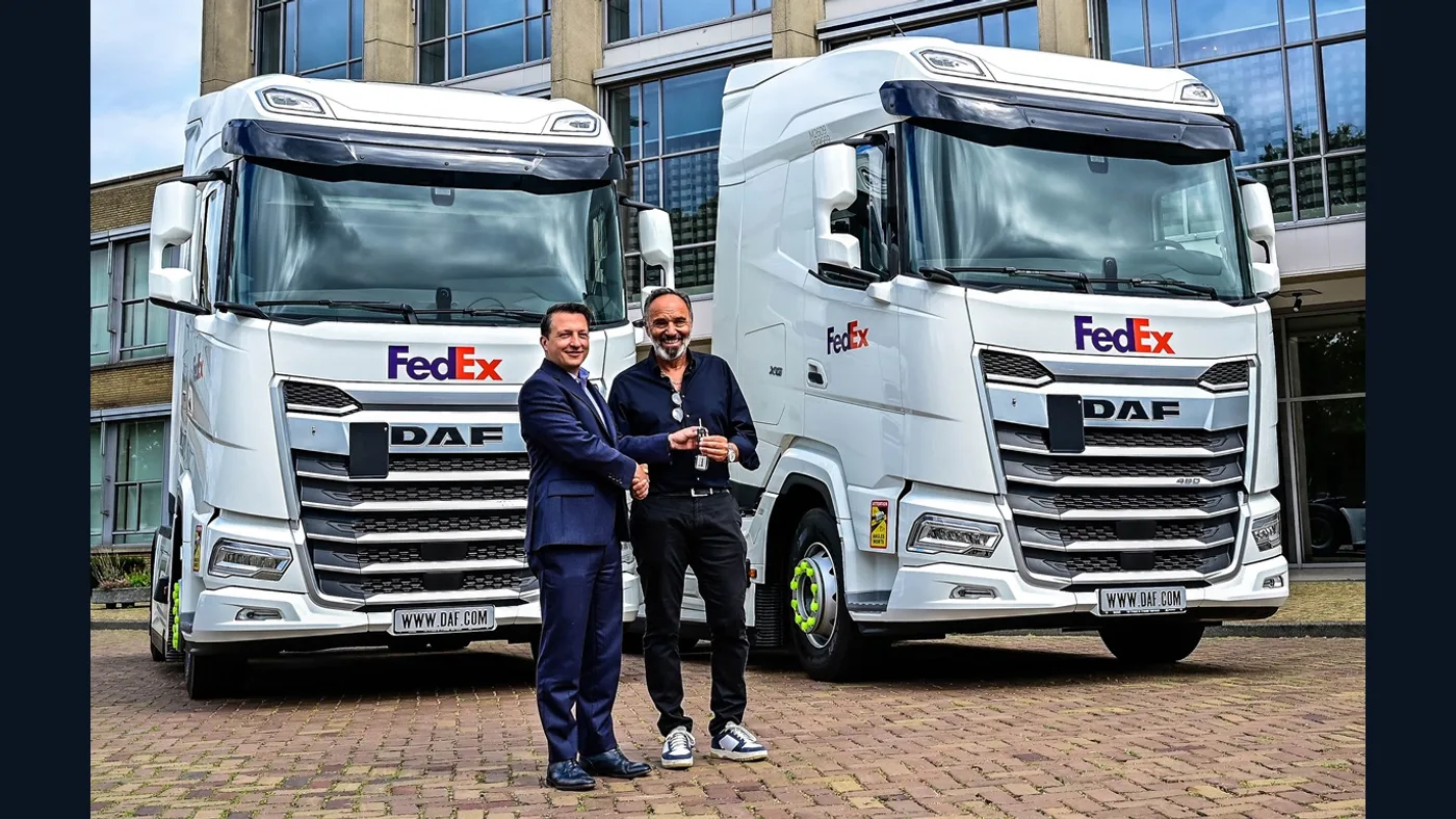 Dos camiones DAF blancos con logotipos FedEx junto a representantes durante la entrega de las primeras unidades