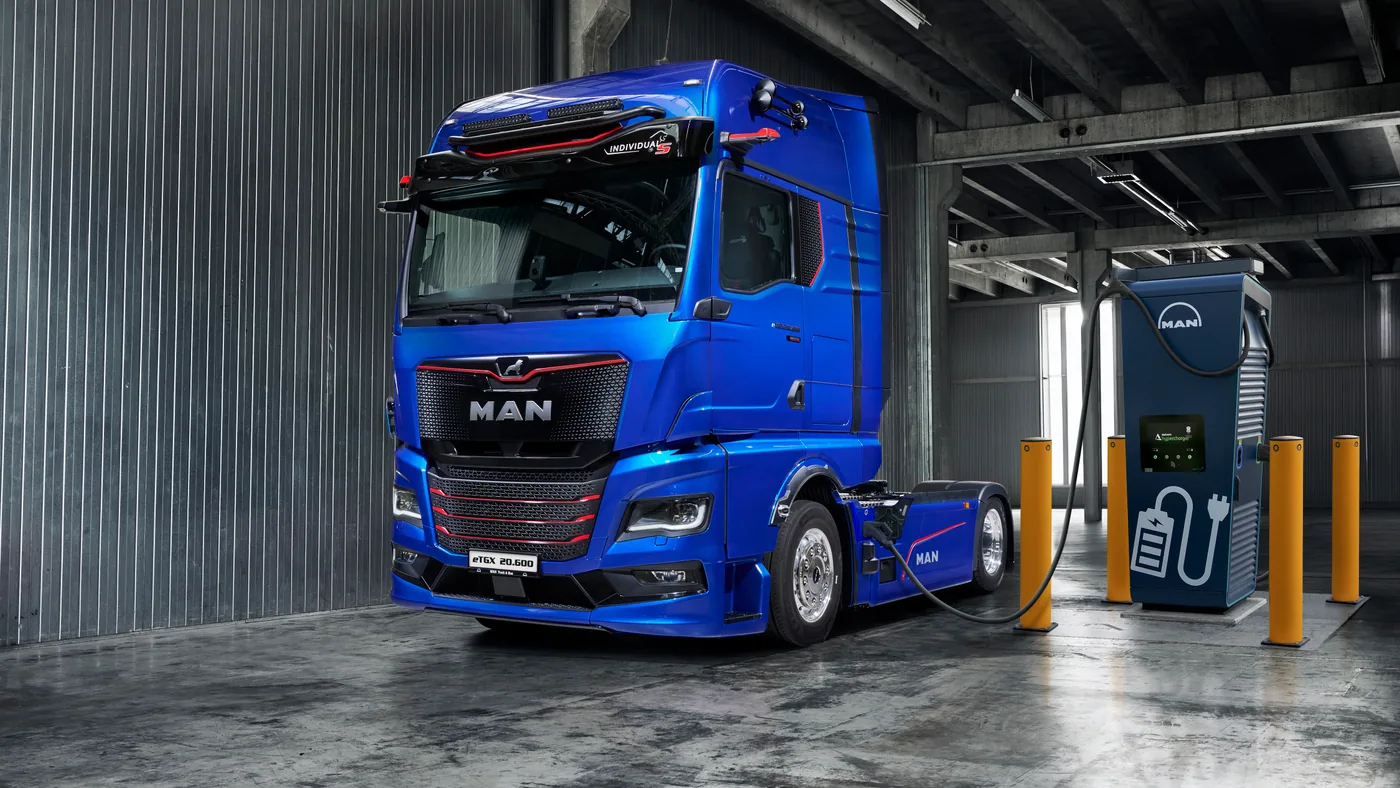 MAN eTGX azul estacionado junto a un cargador en una instalación industrial