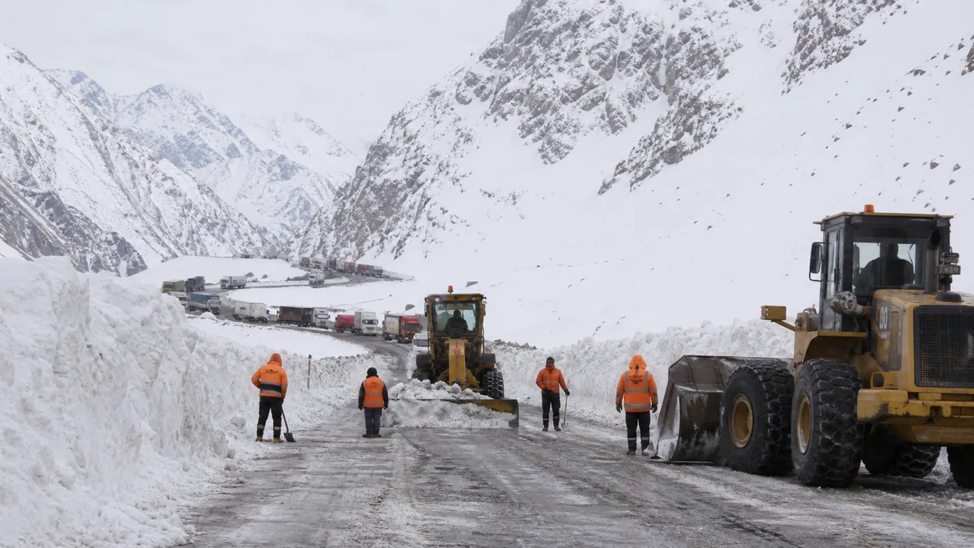 Equipos viales despejando nieve en una ruta de alta montaña con camiones en espera