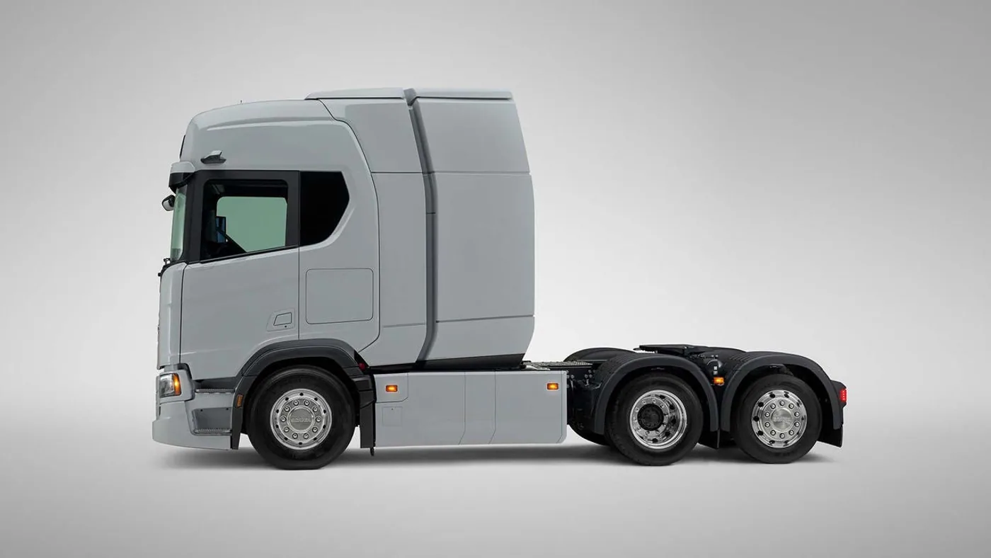 Vista lateral de un tractor Scania eléctrico gris con módulo detrás de la cabina