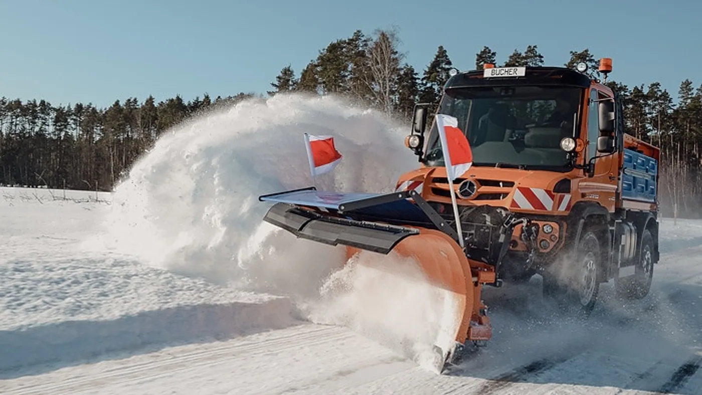 Unimog naranja retirando nieve con una pala frontal