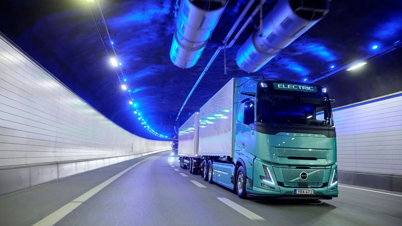Volvo eléctrico verde con carrocería y remolque circulando dentro de un túnel
