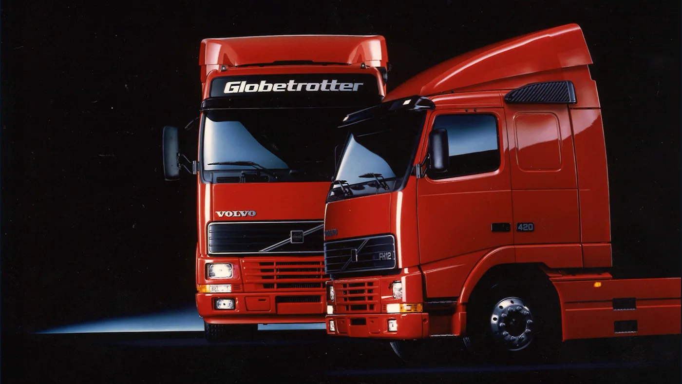 Dos camiones Volvo FH rojos de primera generación fotografiados en 1993 contra un fondo oscuro