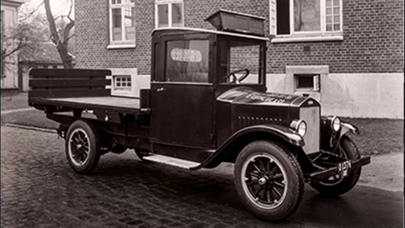 Primer camión Volvo Serie 1 de 1928 con caja de carga abierta fotografiado frente a un edificio